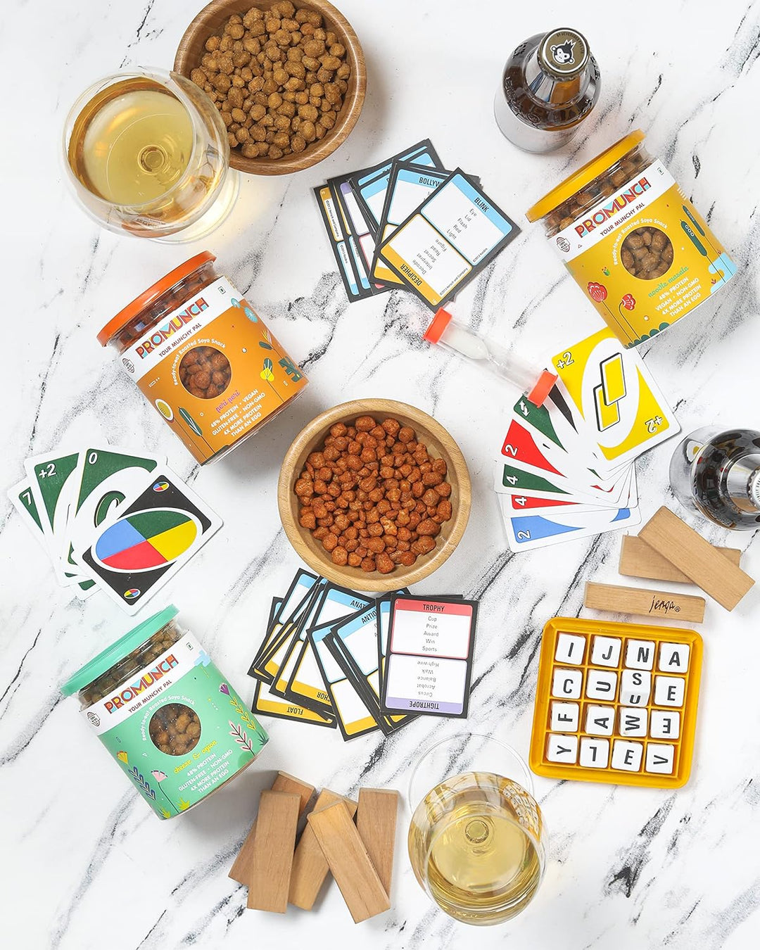 A cozy game night setup with cards, board games, drinks, PROMUNCH soya snacks, and lit candles, creating the perfect vibe for fun and laughter with friends.