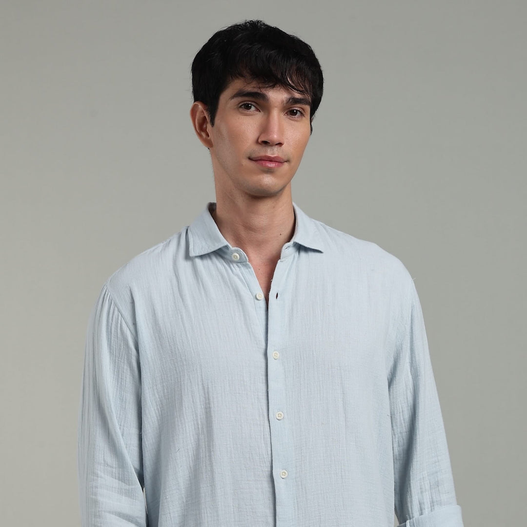 Man wearing a light blue shirt against a gray background