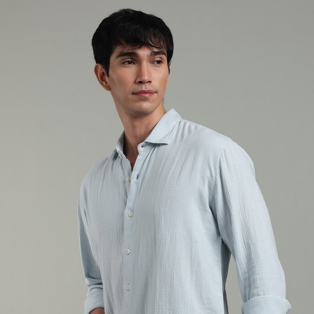 Man wearing a light blue shirt against a gray background