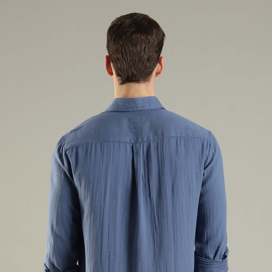 Man wearing a blue shirt from behind on a plain background