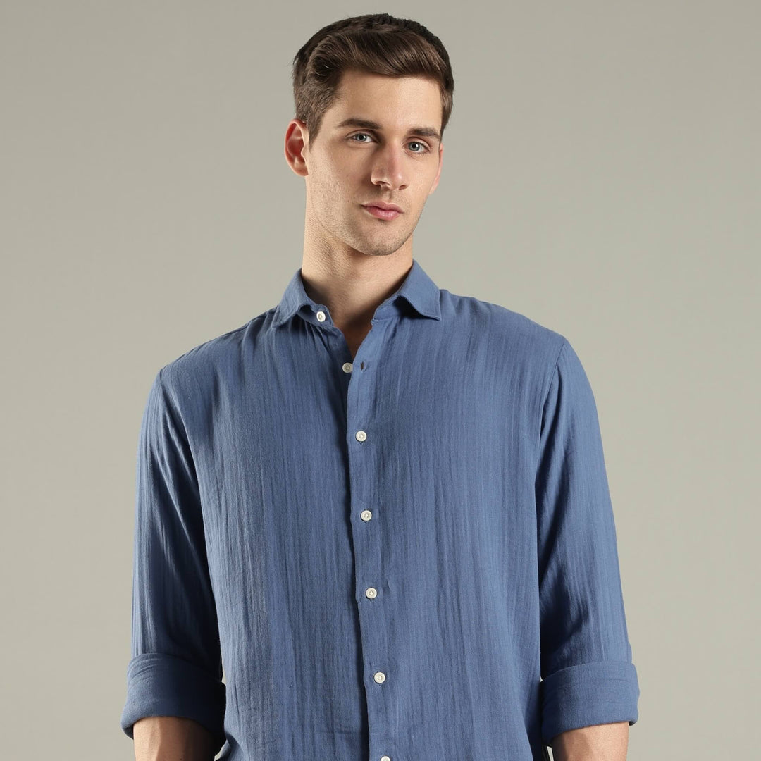 Man wearing a blue button-up shirt against a plain background