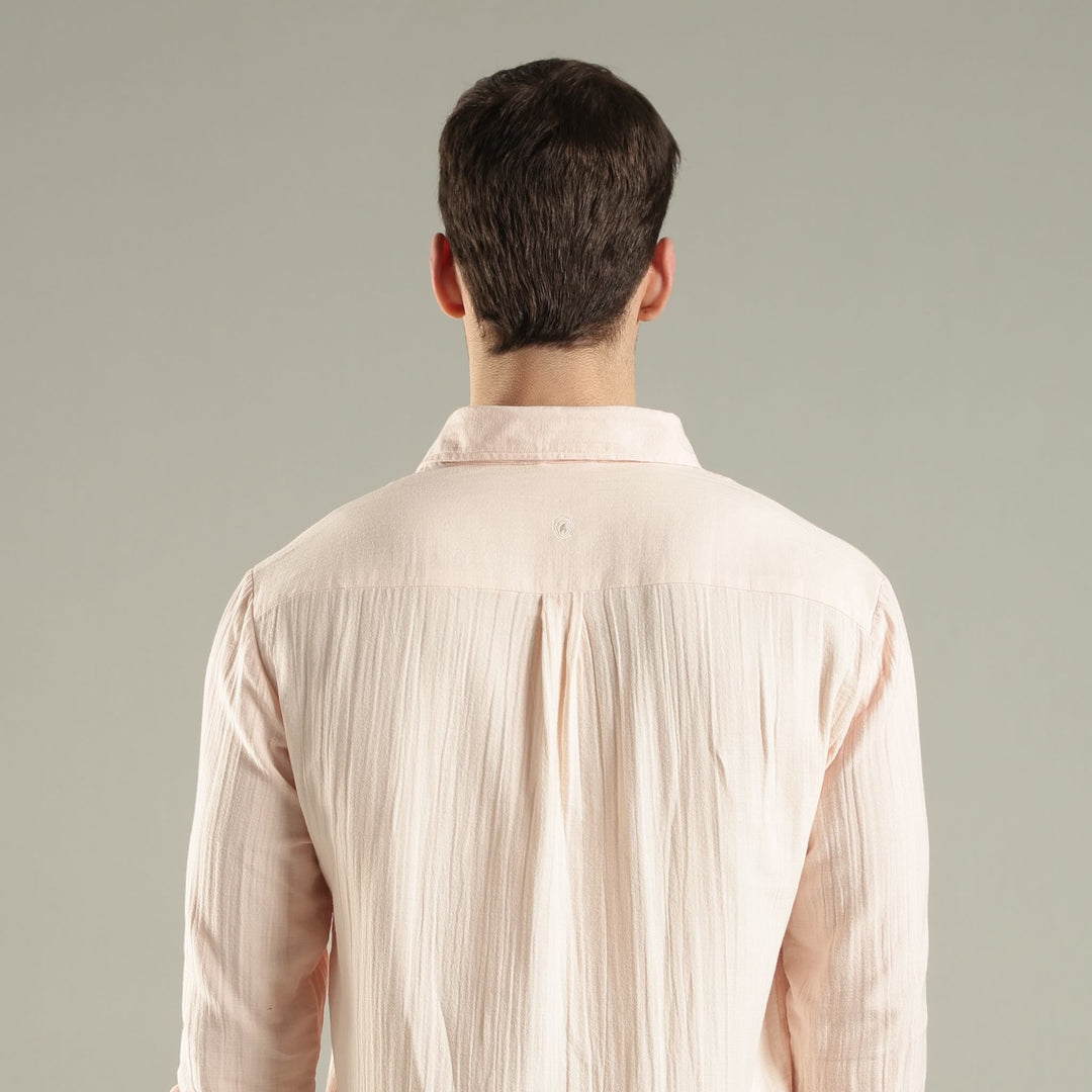 Man wearing a light pink shirt from behind on a gray background
