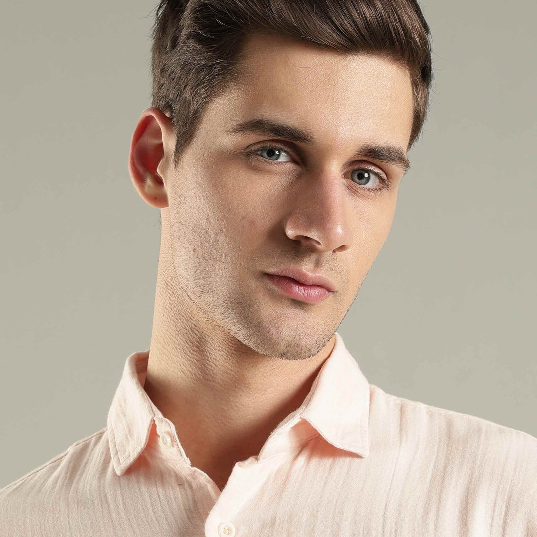 Man wearing a light pink shirt against a neutral background