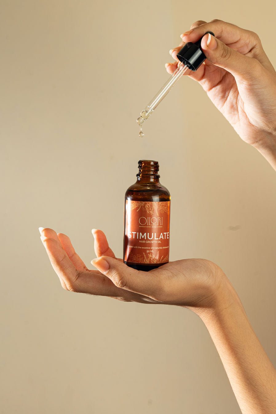 Hand holding a dropper over a bottle labeled &