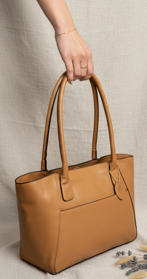 Athena caramel plant-based leather tote bag held by hand highlighting structure, texture and craftsmanship