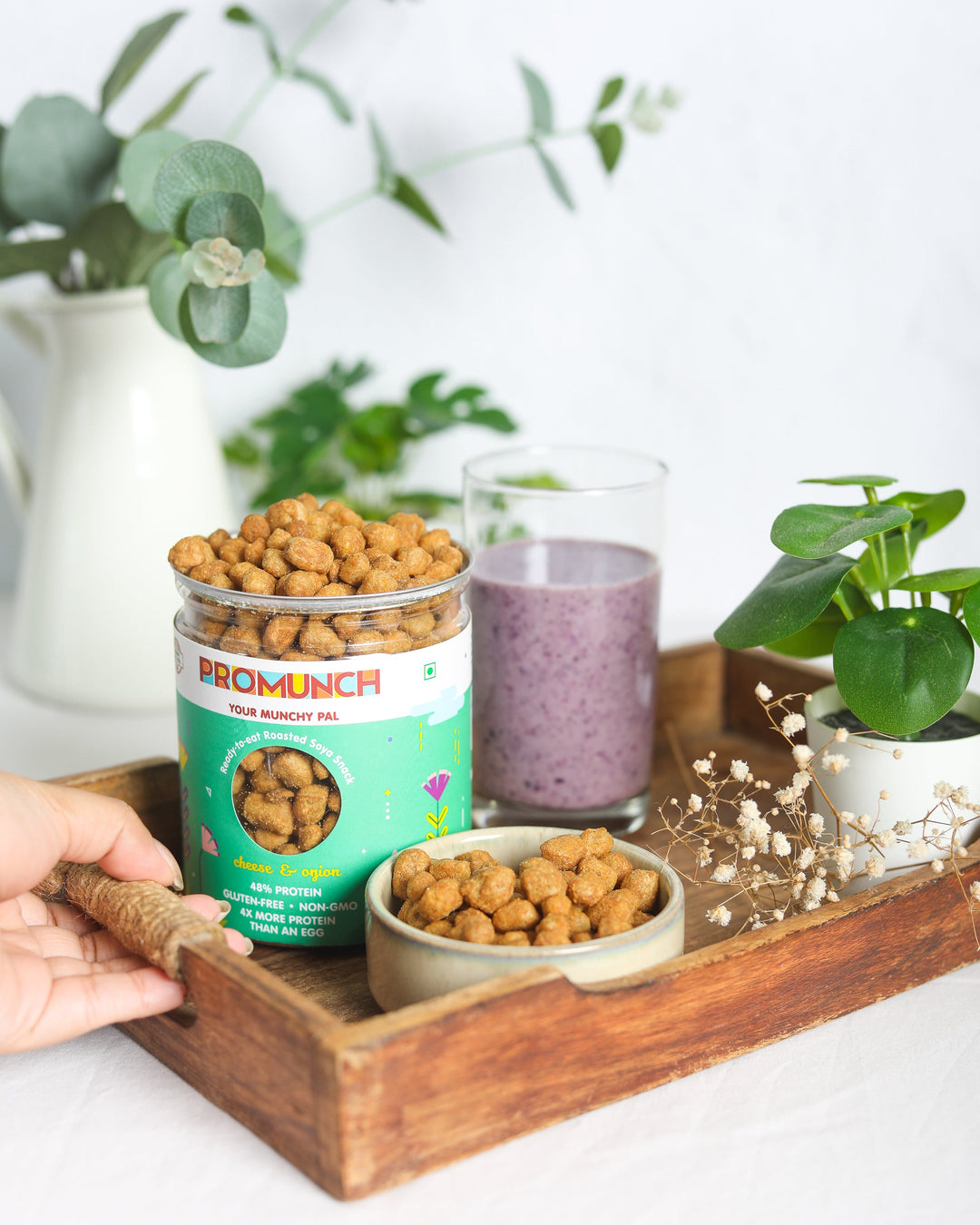Cheese & Onion roasted soya snack presented in a rustic wooden tray, paired with a refreshing berry smoothie and surrounded by lush greenery, showcasing a wholesome and nutritious snack-time setup